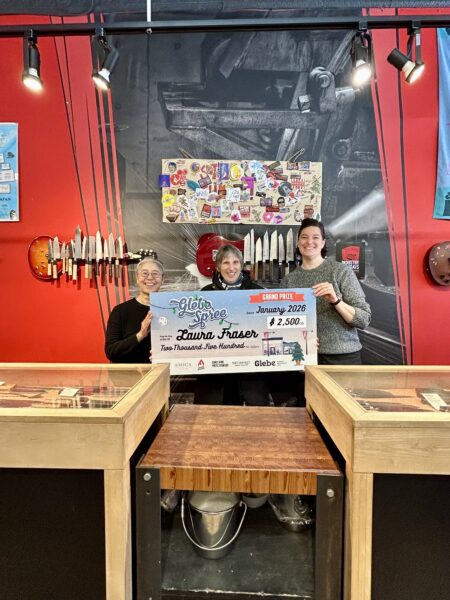 A giant Glebe Spree grand prize cheque held up inside a Bank Street shop