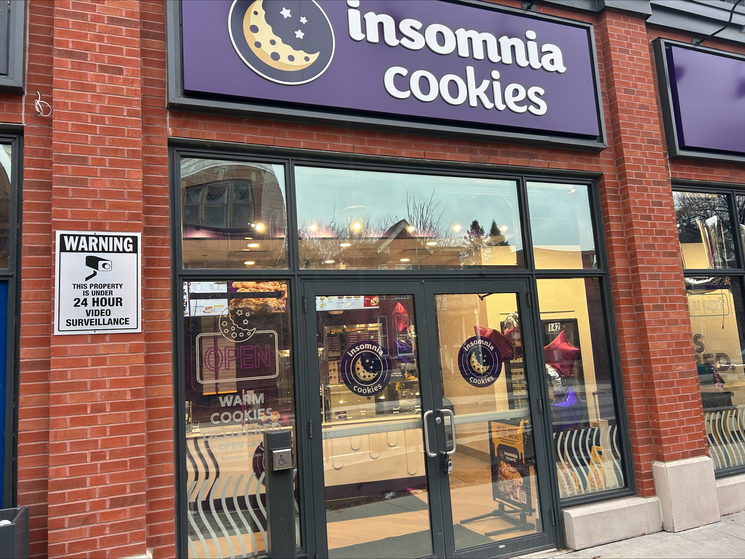 The brick storefront of Insomnia Cookies on Bank Street, warm lights on inside